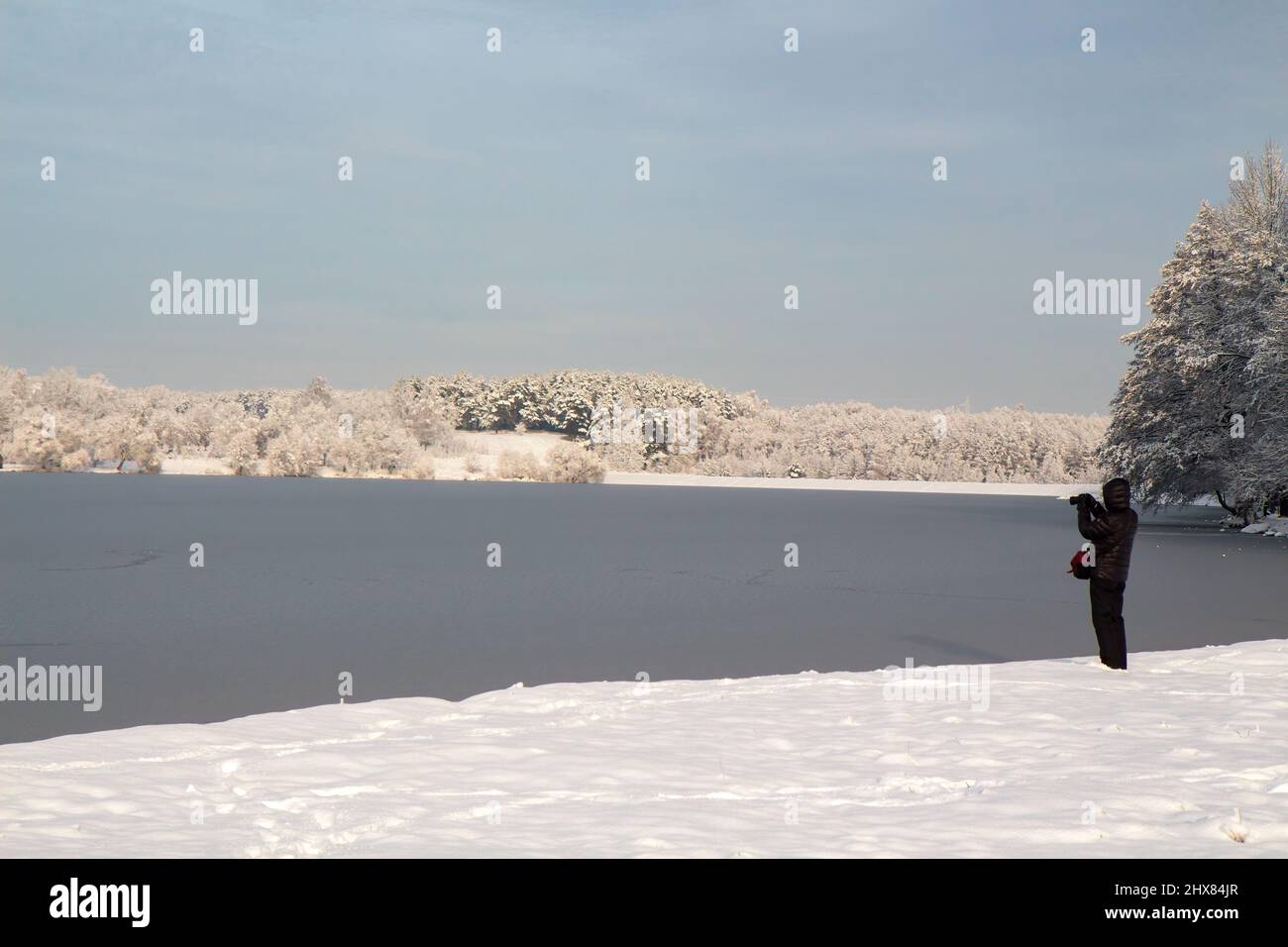 MINSK, BÉLARUS - 10 DÉCEMBRE 2017 : un homme photographie un paysage d'hiver. Lac sous la glace, arbres enneigés, gel, neige, journée claire. Banque D'Images