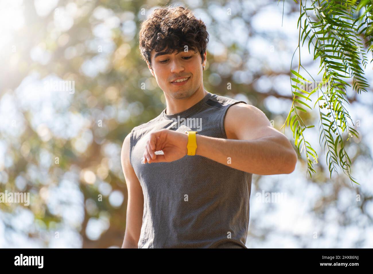 Un jeune homme qui fait du sport regarde la montre intelligente et rient dans le parc Banque D'Images