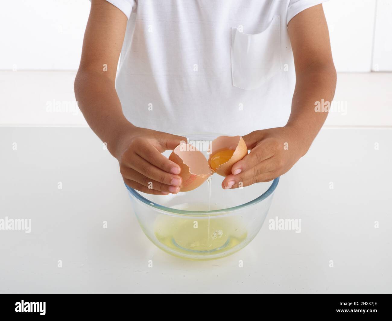 garçon cassant un œuf dans un bol Banque D'Images