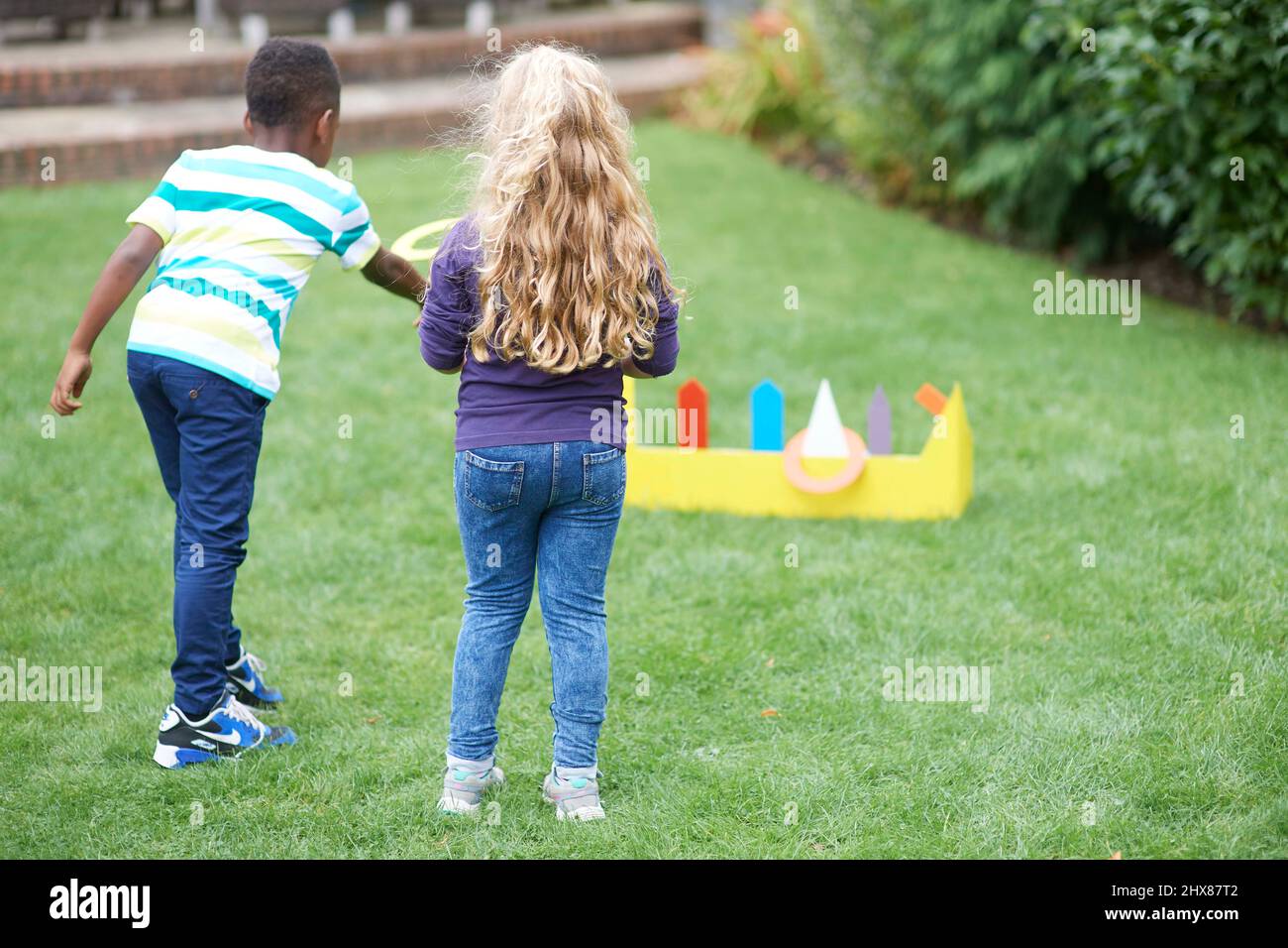 Les enfants jouent dans le jardin avec un jeu de jeu d'anneau en carton Banque D'Images