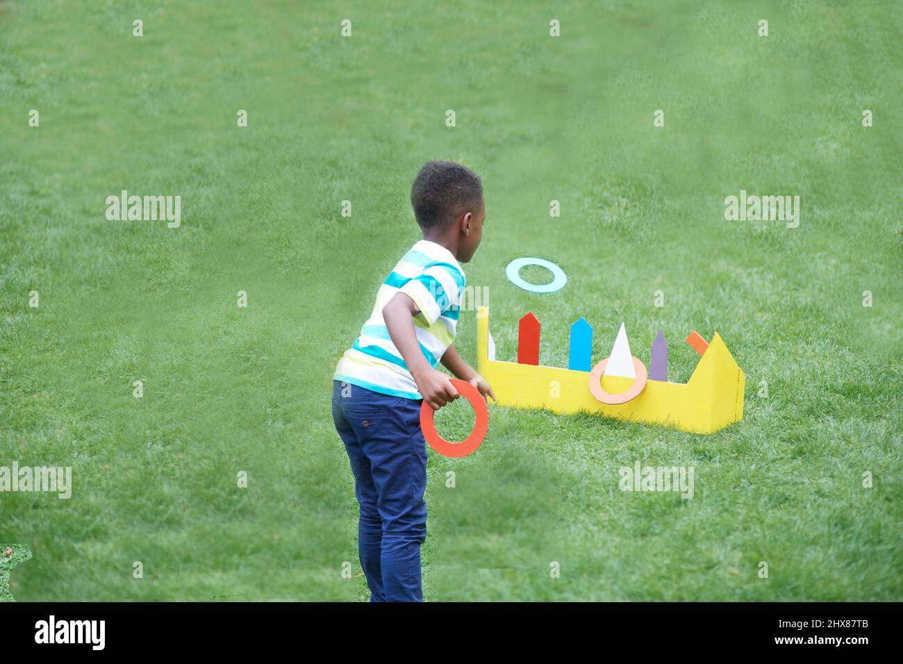 Les enfants jouent dans le jardin avec un jeu de jeu d'anneau en carton Banque D'Images