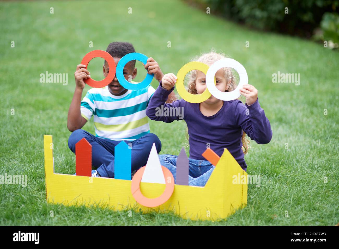 Les enfants jouent dans le jardin avec un jeu de jeu d'anneau en carton Banque D'Images