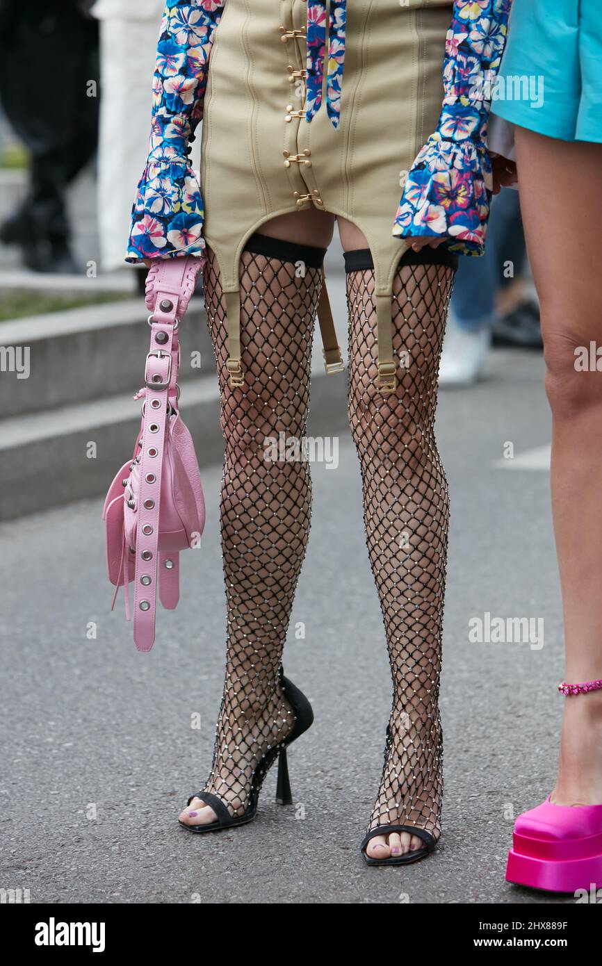 MILAN, ITALIE - 24 FÉVRIER 2022: Femme avec bas filet noir avec détails dorés et sac en cuir rose avant le spectacle de mode Emporio Armani, Milan Fa Banque D'Images