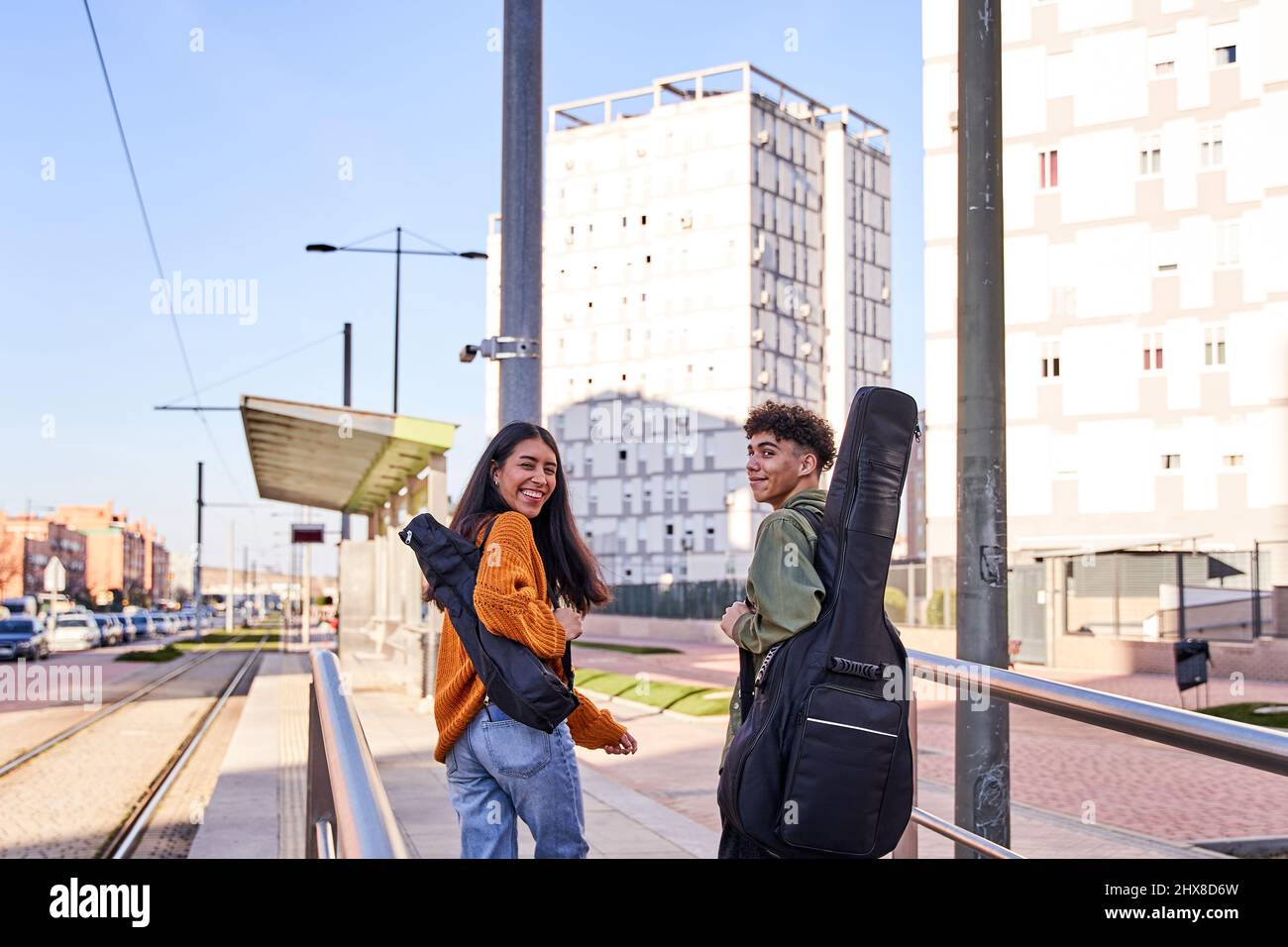 les étudiants de musique sur leur chemin vers la gare. ils se retournant dans une rue urbaine avec le sourire. les étudiants de guitare et ukulele avec leur instrument Banque D'Images