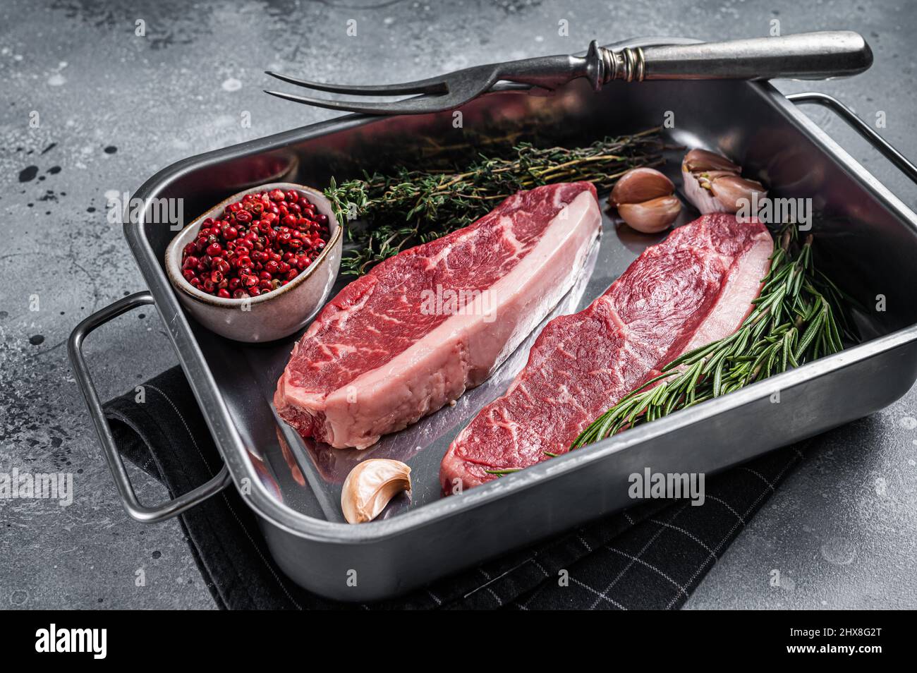 Bœuf de bœuf haché cru ou steak de bœuf de bœuf haché dans le plateau avec des herbes.Arrière-plan gris.Vue de dessus Banque D'Images