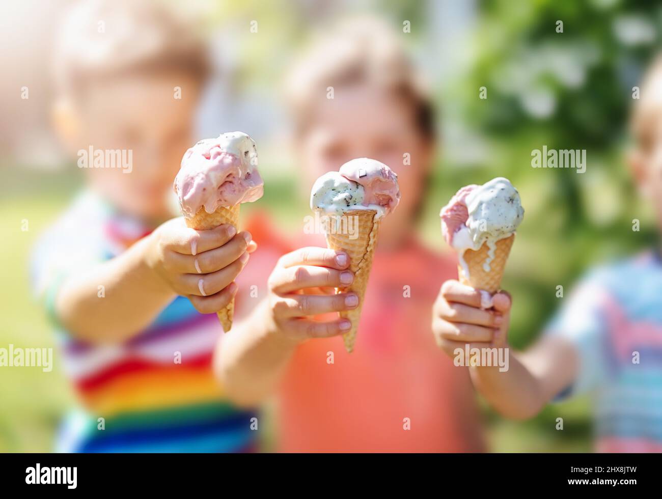 Groupe d'enfants du parc qui mangent de la crème glacée froide. Banque D'Images