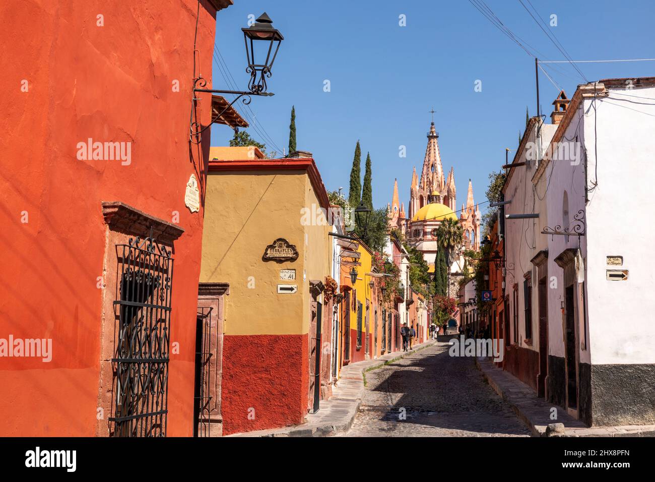 Mexique, Guanajuato, San Miguel de Allende, une rue latérale de la ville avec des maisons et des magasins menant à la ville avec Parroquia de San Miguel Arcángel Banque D'Images