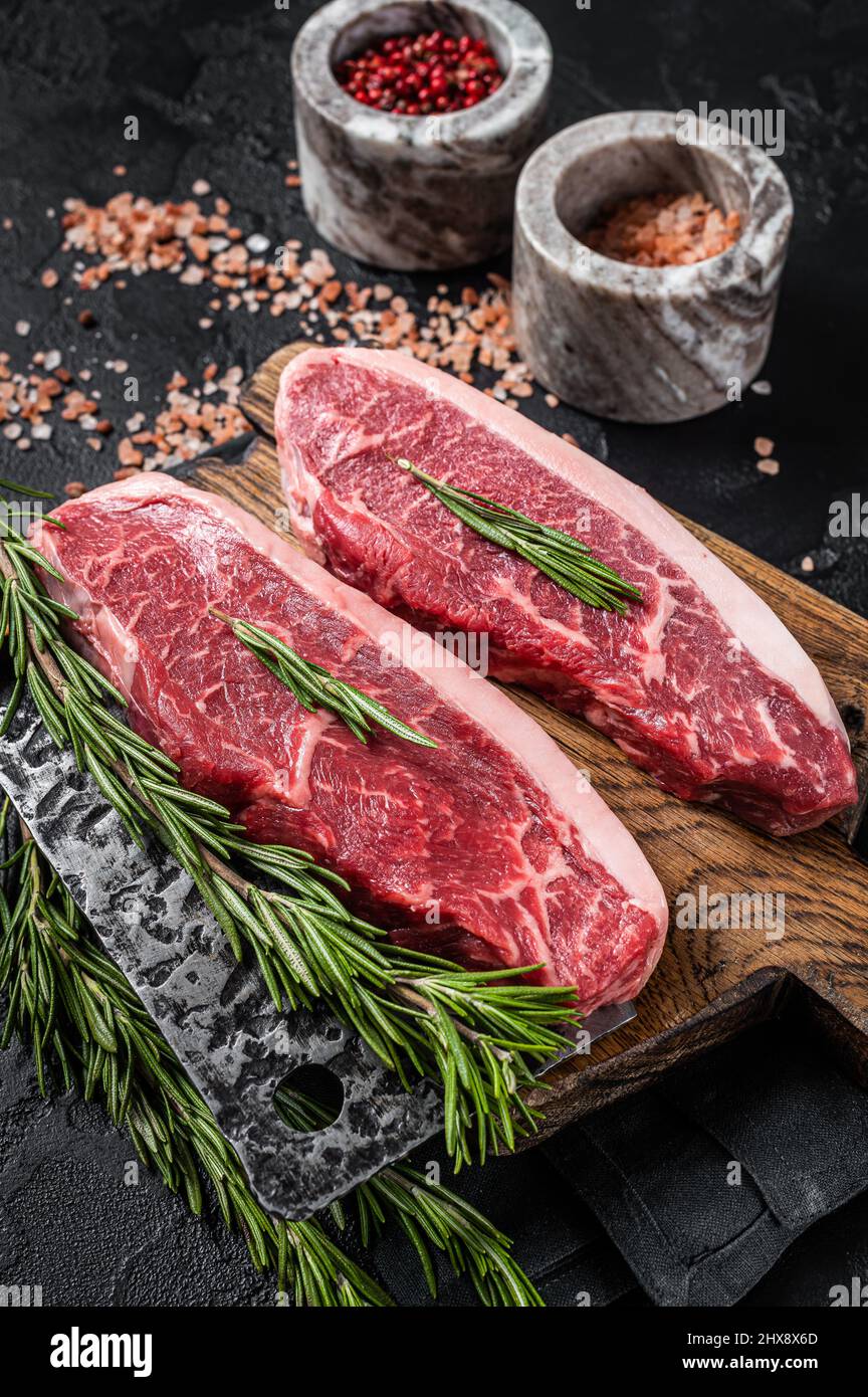 Steak de viande de bœuf de boucherie ou sirloin sur le dessus du butcher.Arrière-plan noir.Vue de dessus Banque D'Images