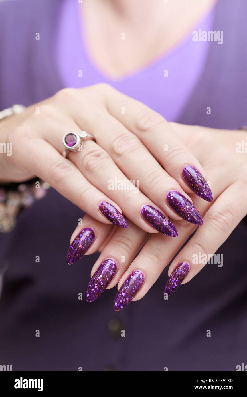 Main féminine avec ongles longs et manucure aux prunes violettes une  bouteille de vernis à ongles Photo Stock - Alamy