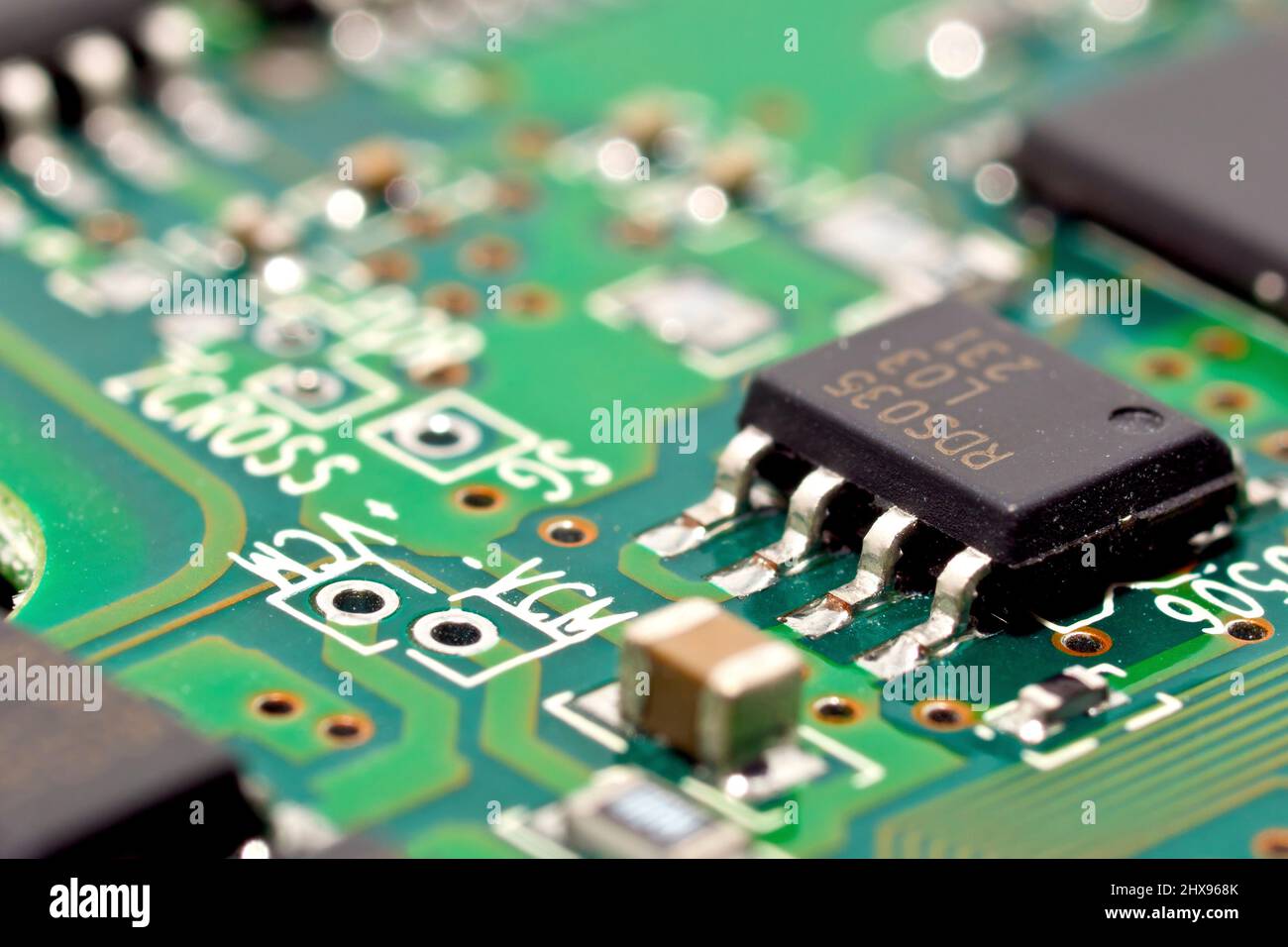 Gros plan sur une carte de circuit imprimé, en se concentrant sur une seule puce intégrée connectée aux circuits imprimés d'une carte de circuit imprimé. Banque D'Images
