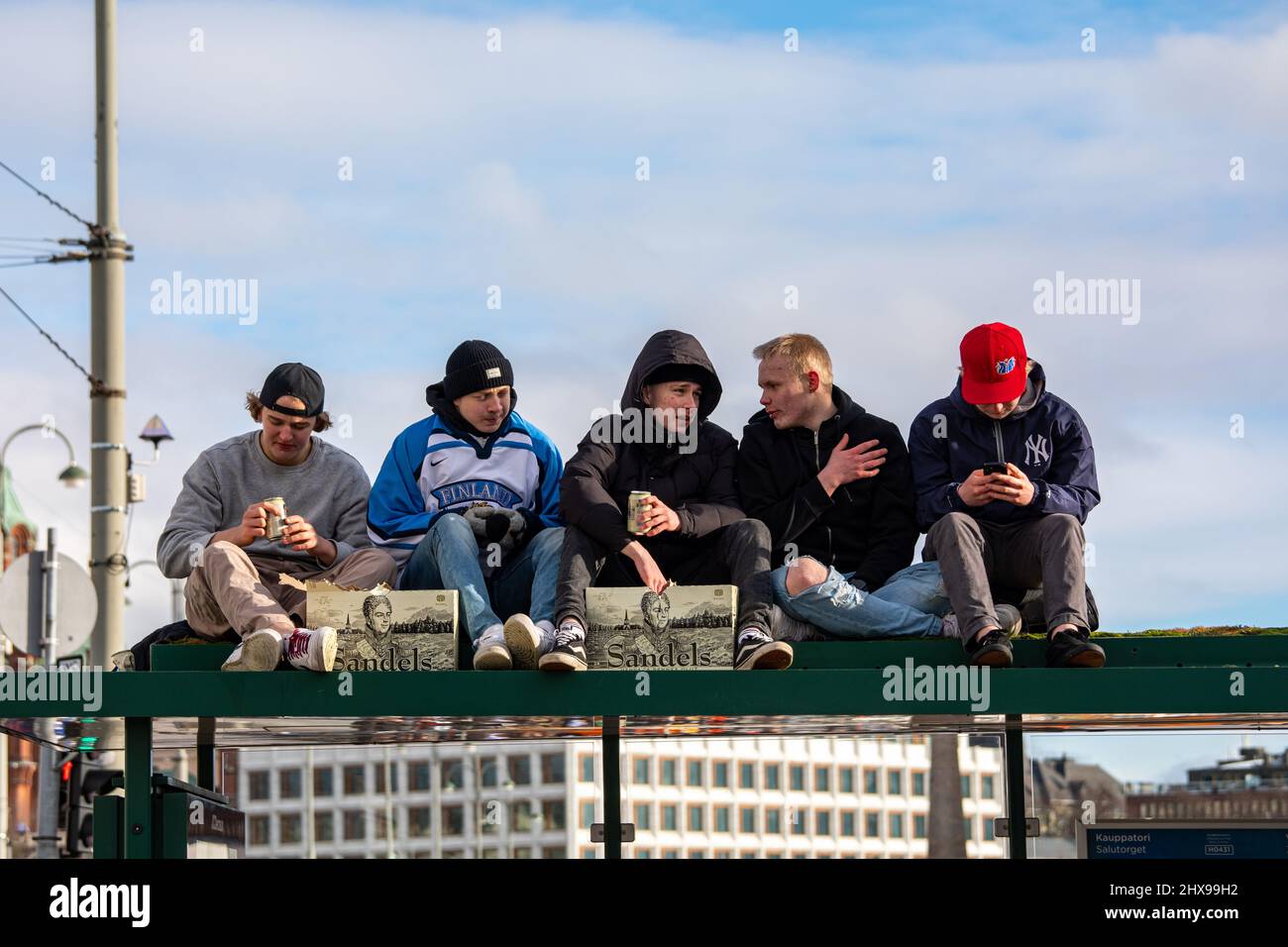 Les jeunes hommes assis sur le tramway s'arrêtent sur le toit pour boire de la bière tout en célébrant la toute première médaille d'or de hockey olympique de Finlande à Helsinki, en Finlande Banque D'Images