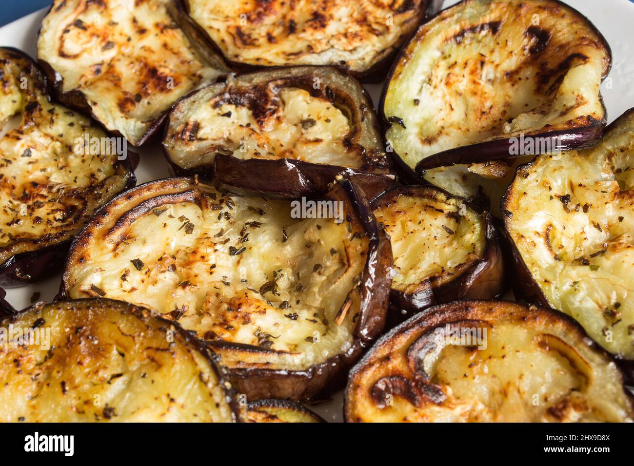 Détail d'une tranche d'aubergine rôtie au four avec le reste des légumes coupés entouré comme fond. Recettes simples et végétariennes. Banque D'Images