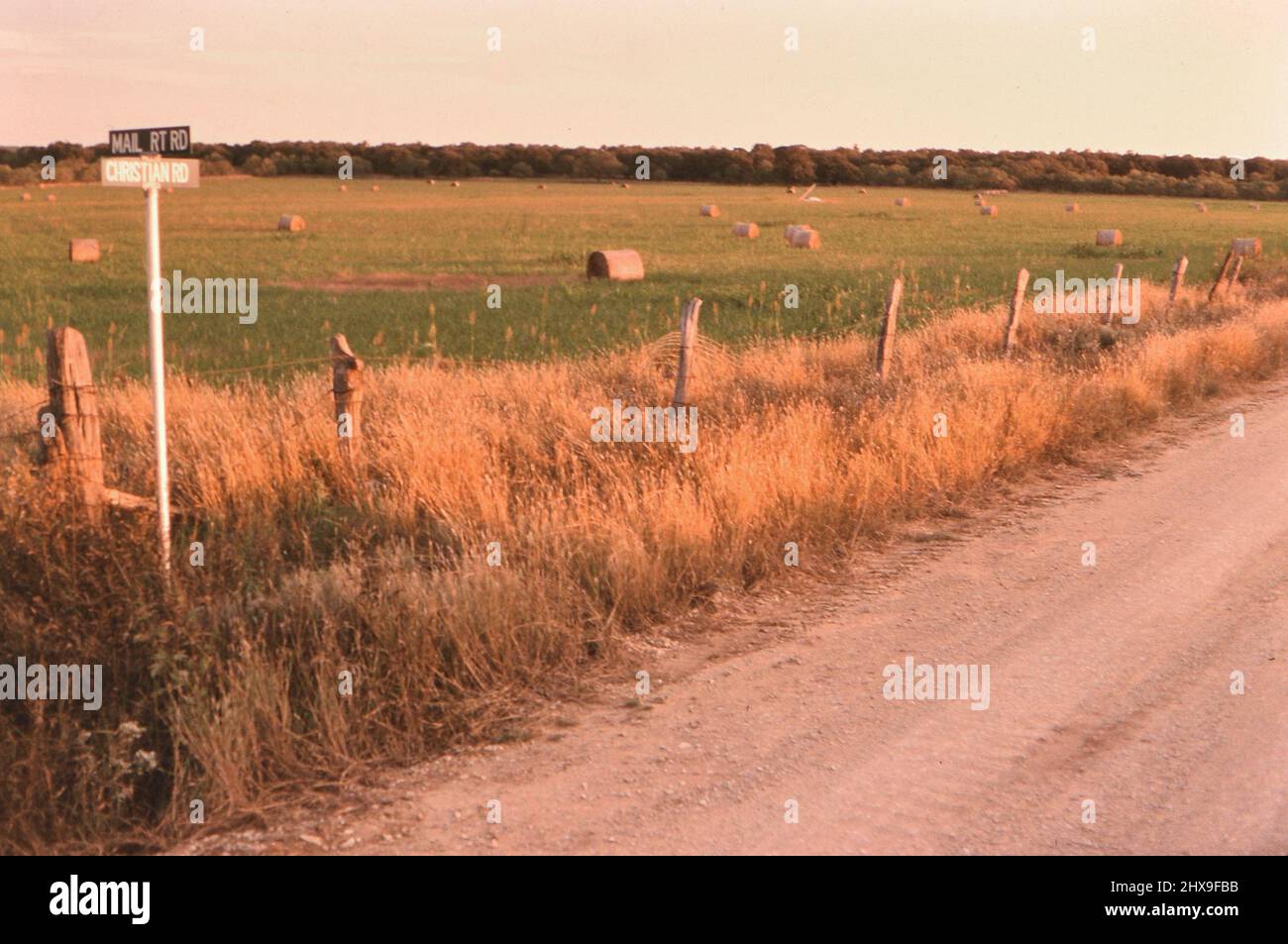 Balles rondes de foin dans un champ dans le Texas rural, le panneau routier rural montre Christian Road ca. 1996 Banque D'Images