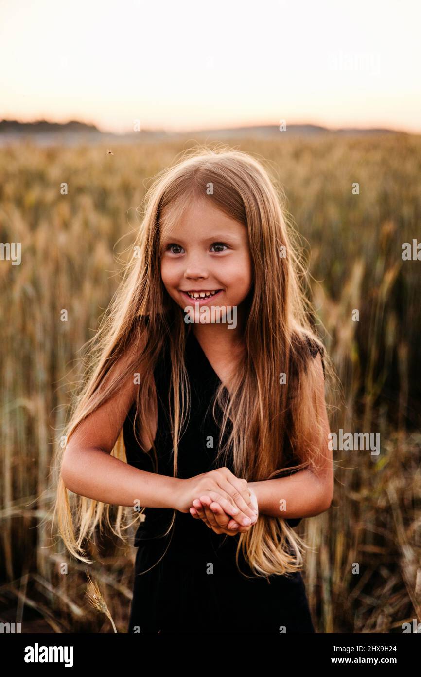 Bonne petite fille s'amuser dans un champ de blé doré lors d'une journée ensoleillée d'été. L'été Banque D'Images