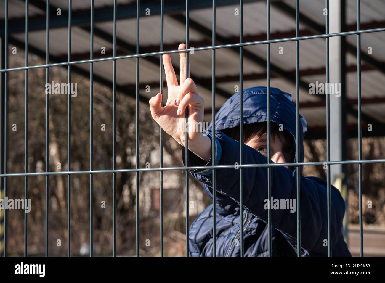 Main d'un enfant réfugié tenant une clôture en métal. Problème social des migrants de guerre. Banque D'Images