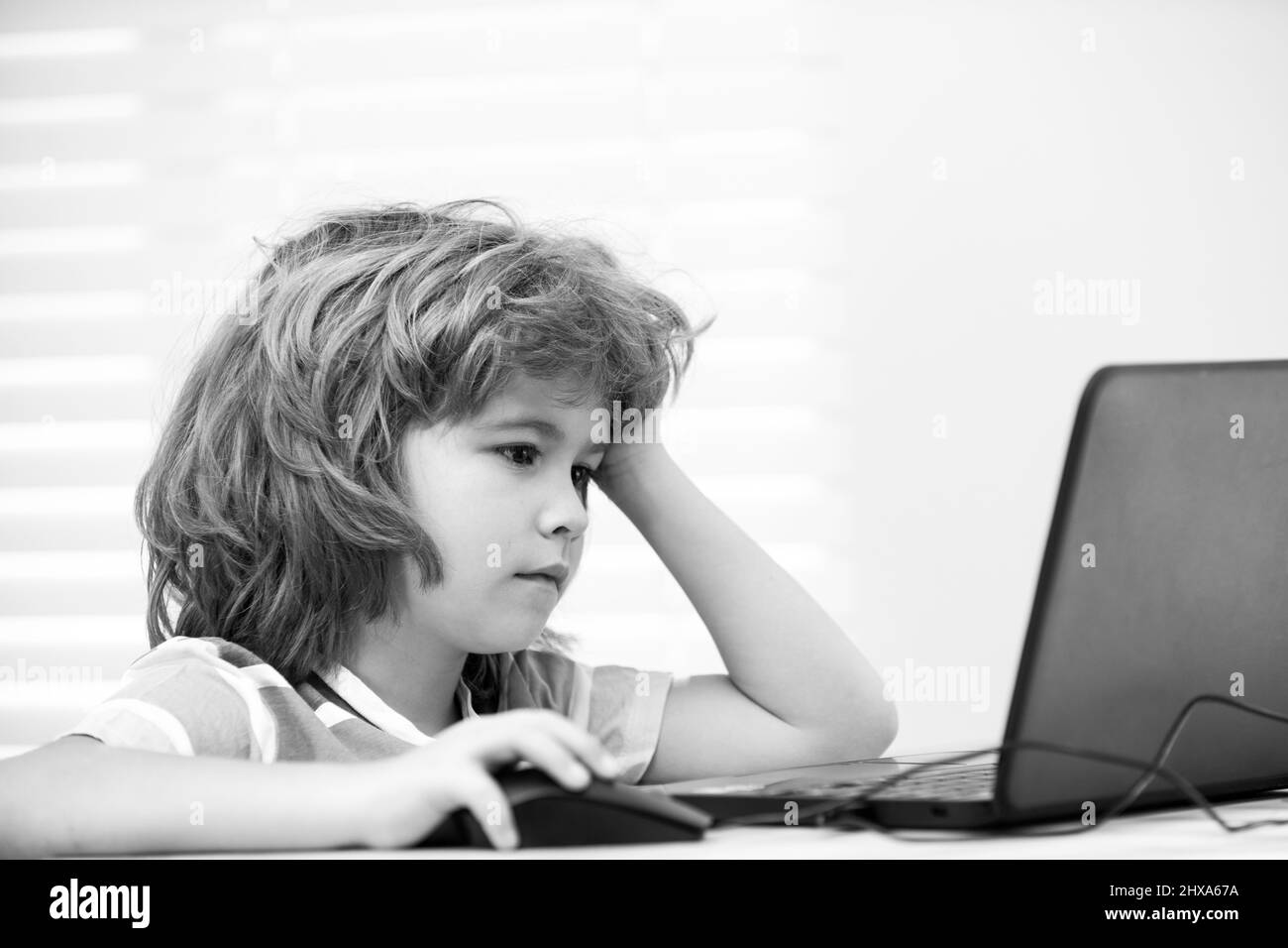 Portrait d'un garçon d'école regardant l'ordinateur portable pendant la leçon. Éducation et apprentissage de l'enfant. Banque D'Images