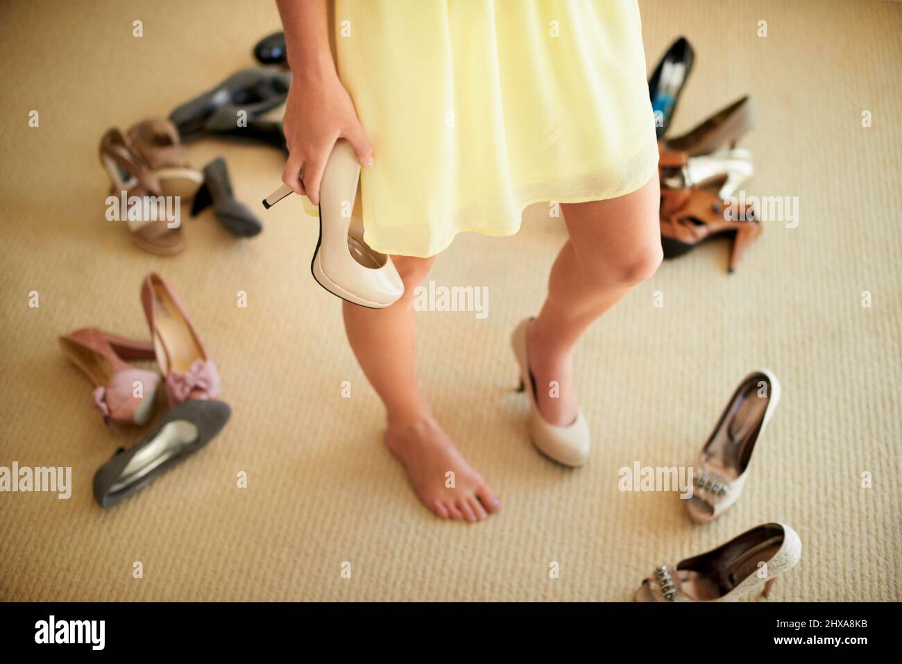Trouver un équilibre entre style et confort. Image rognée d'une femme debout dans sa chambre entourée de chaussures. Banque D'Images