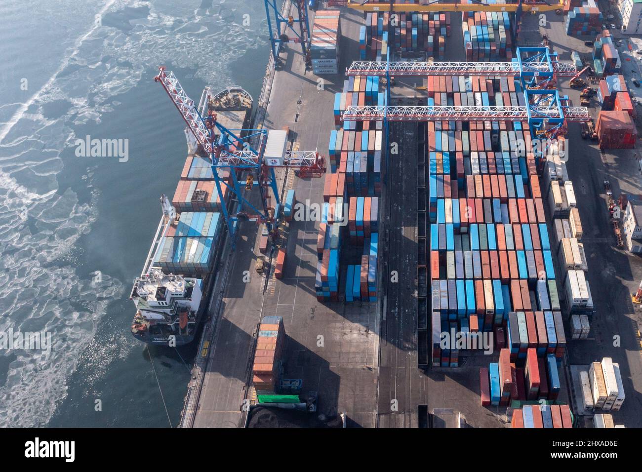Vladivostok, Russie - 27 janvier 2022 : Vue de dessus du terminal des conteneurs du port maritime. En hiver, un bateau à conteneurs est en train de charger au quai. Banque D'Images