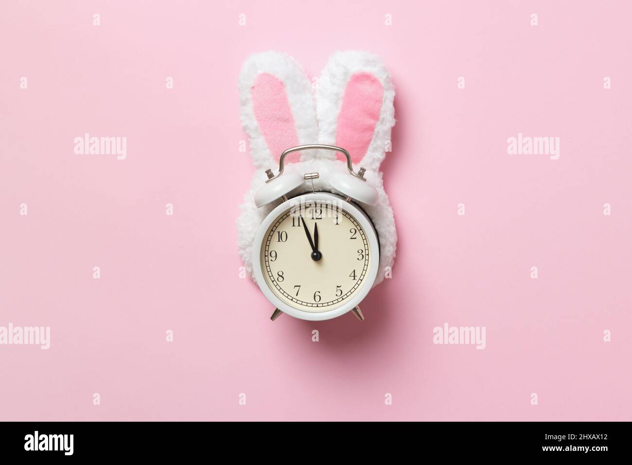 Heure de Pâques. Réveil dans les oreilles de lapin sur fond rose. Banque D'Images