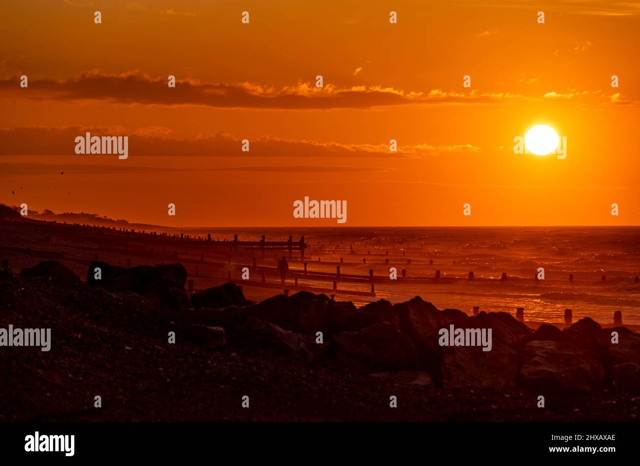 Rustington Beach, Royaume-Uni, 11th mars 2022. Le soleil se lève lorsqu'un chien promenant se promène le long de la plage de Rustington, dans le West Sussex. Crédit : Steven Paston/Alay Live News Banque D'Images