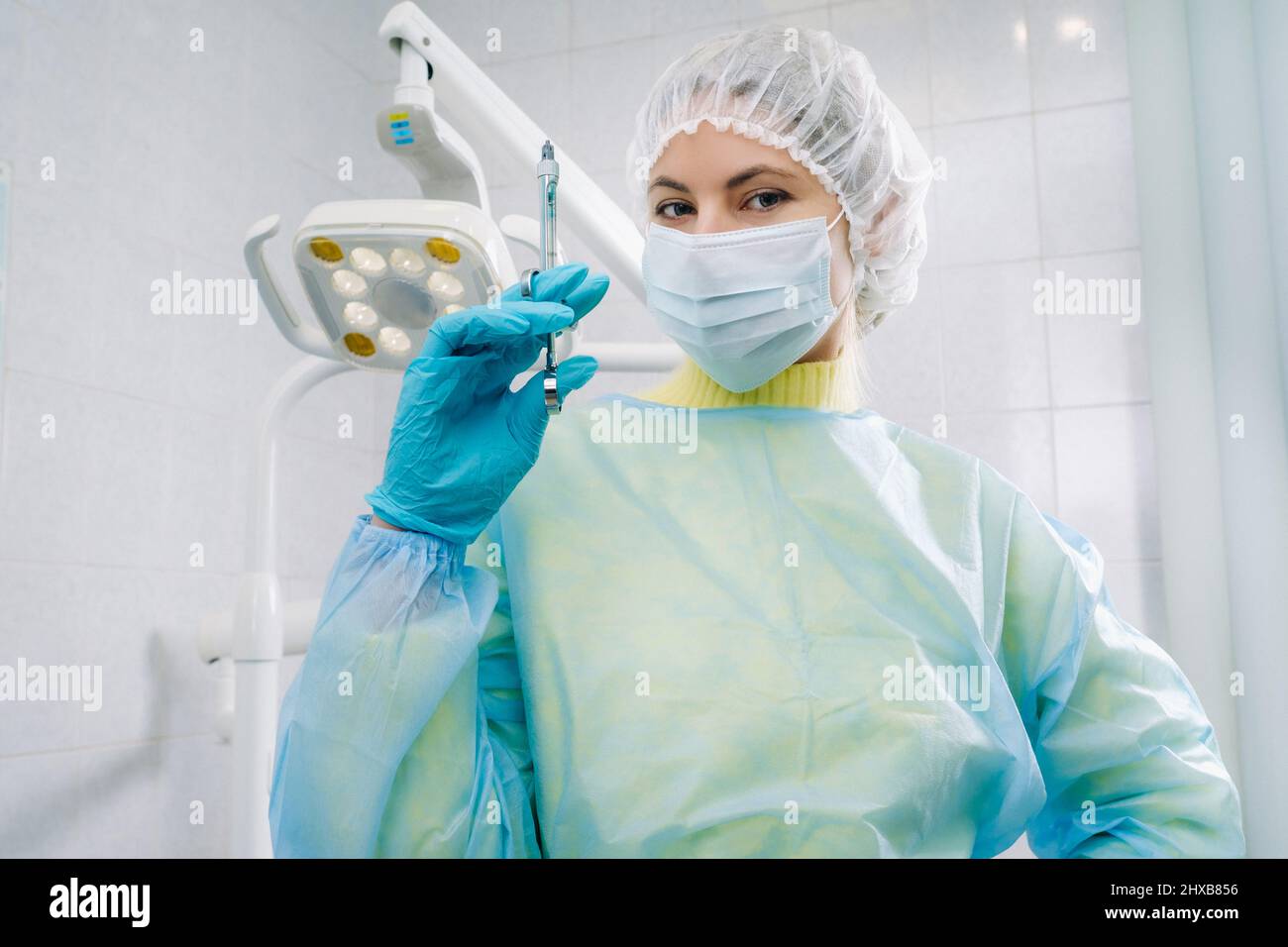 Un dentiste masqué tient une seringue d'injection pour un patient au bureau. Banque D'Images