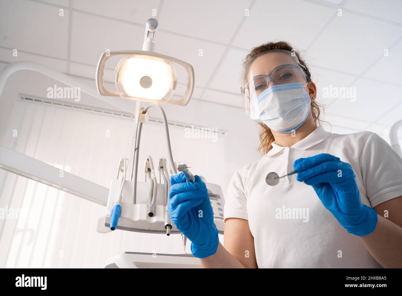 Femme dentiste seule tenant des instruments dentaires, regardant la caméra. Point de vue personnel ou patient, POV. Concept de traitement dentaire. Espace de copie. Banque D'Images
