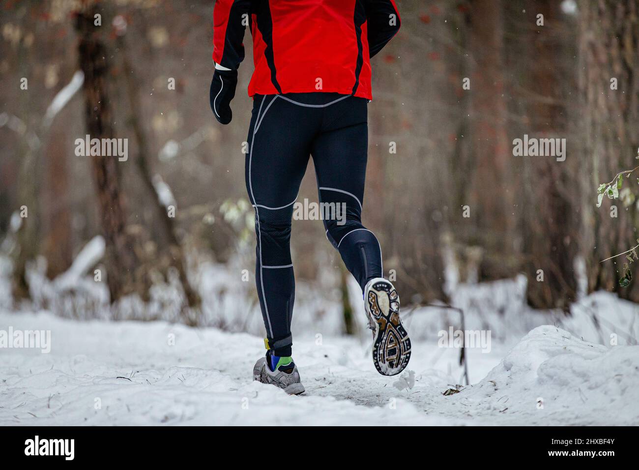 les jambes des coureurs mâles courent dans la forêt d'hiver Banque D'Images