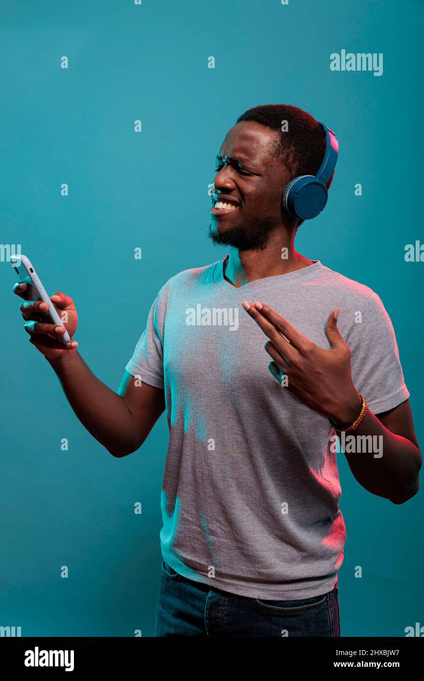 Une personne excitée écoute de la musique sur son micro-casque et sur son  téléphone, en profitant du son de la radio à partir d'un smartphone. Jeune  modèle tenant un gadget moderne et