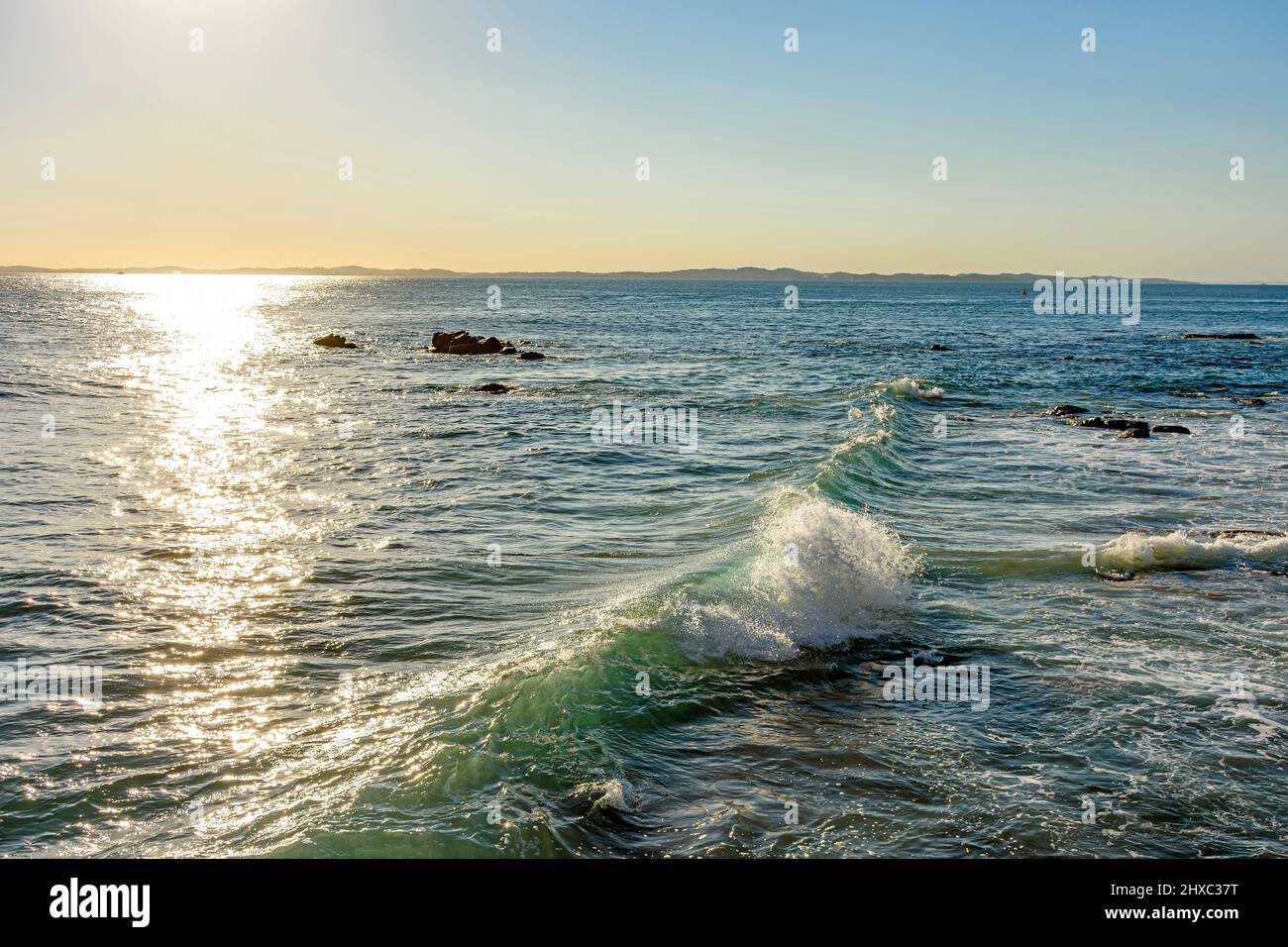 Coucher de soleil sur les eaux de la mer dans la ville de Salvador à Bahia avec de petites vagues se brisant le long des rochers Banque D'Images