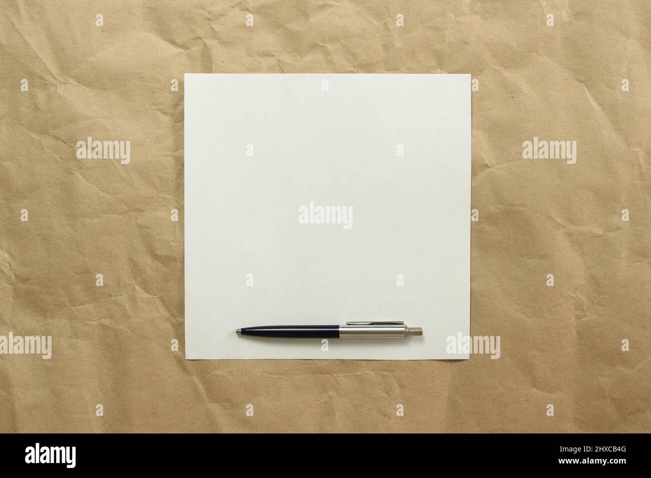 Feuille de papier blanc carré vide avec stylo sur papier beige. Concept d'analyse, d'étude, de travail attentif. Stock photo avec espace vide pour votre texte et votre design. Banque D'Images