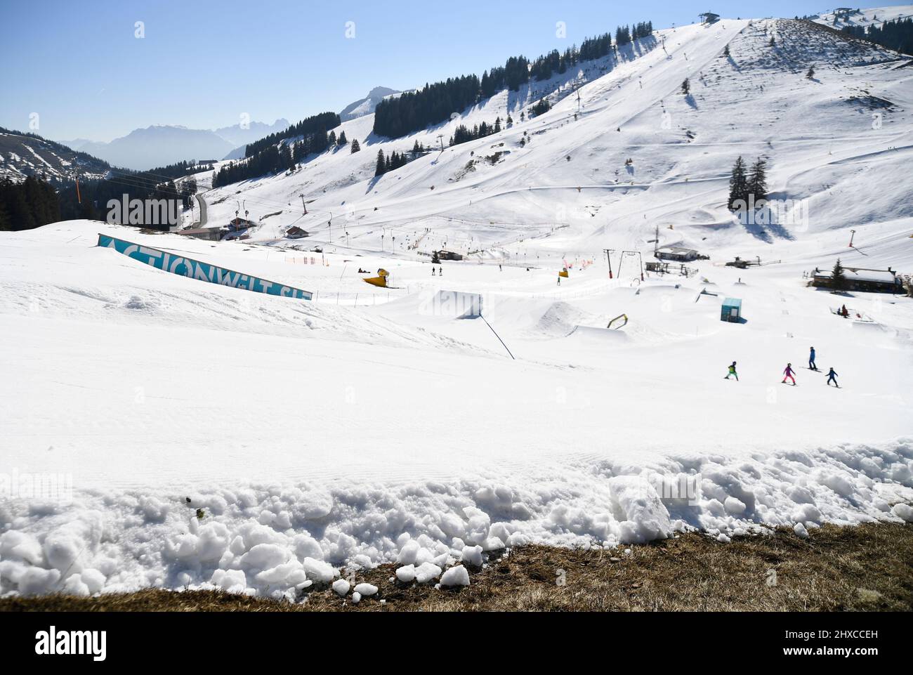 Bayrischzell, Allemagne. 11th mars 2022. Alors que le premier vert est déjà visible en premier plan, les skieurs descendent une pente à Sudelfeld dans les montagnes de Mangfall en haute-Bavière. Credit: Uwe Lein/dpa/Alay Live News Banque D'Images