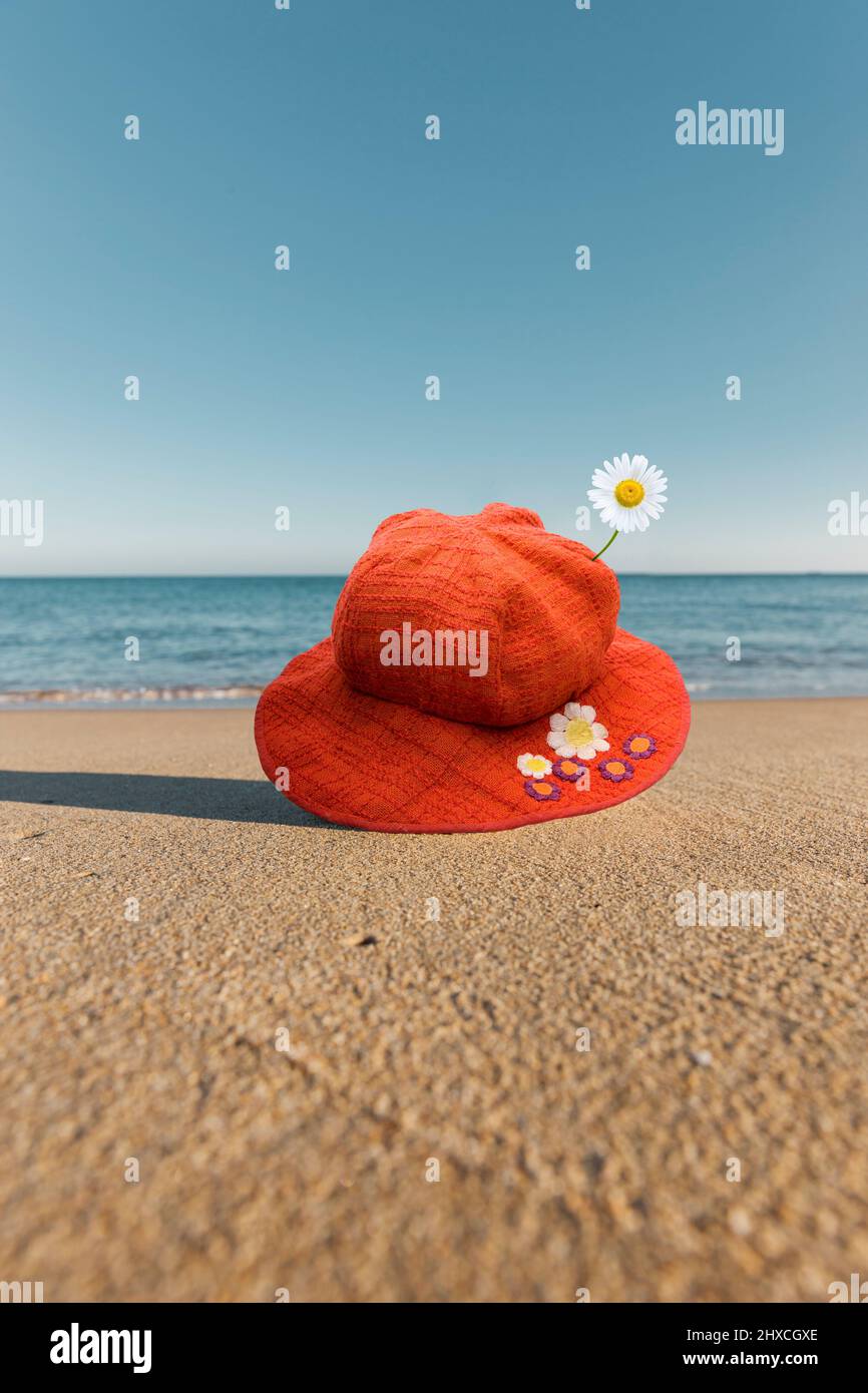 Chapeau de soleil rouge sur le sable au bord de la mer bleue Banque D'Images