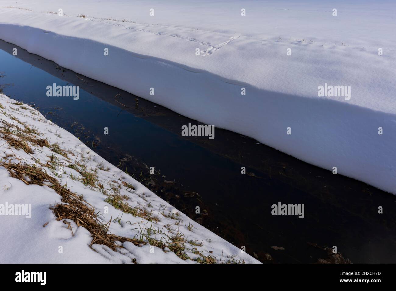 Petite rivière étroite en hiver, beaucoup de neige sur la rive Banque D'Images