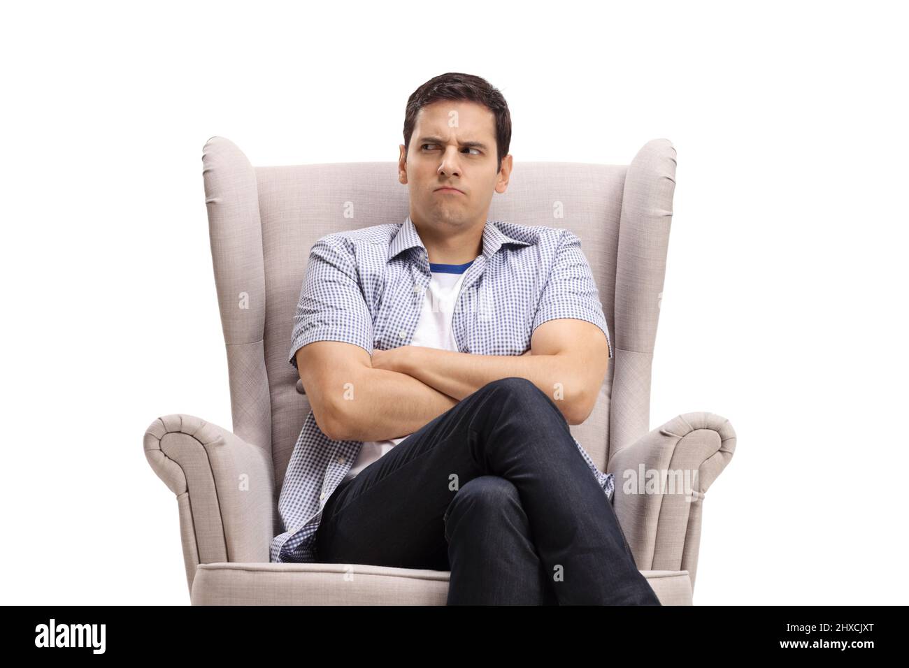 Jeune homme avec un visage en colère assis dans un fauteuil isolé sur fond blanc Banque D'Images