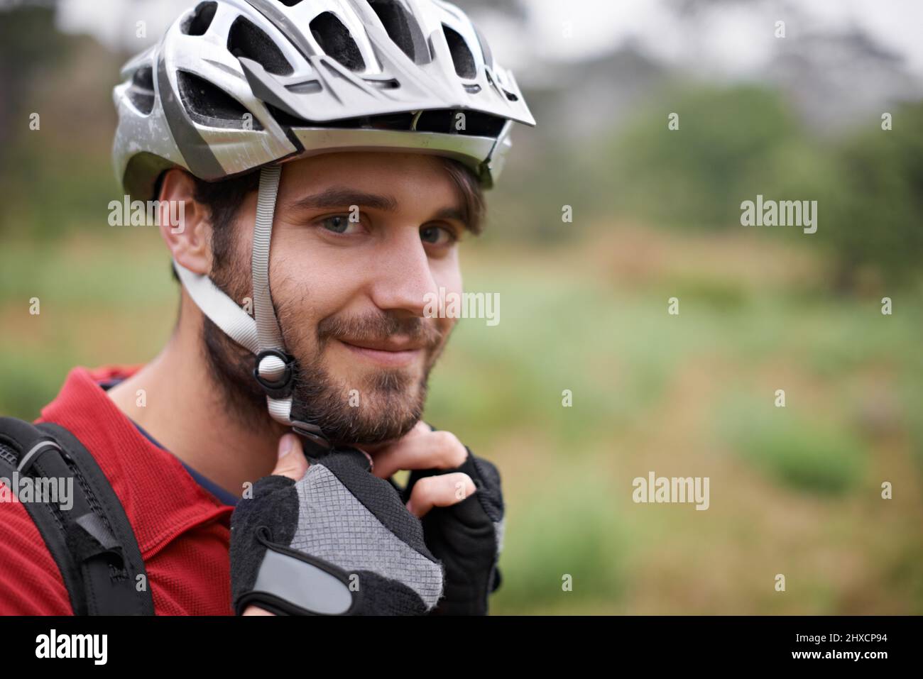 Il est serré. Un jeune cycliste qui attache son casque. Banque D'Images