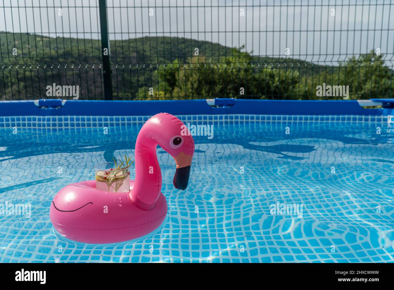 Cocktail à l'intérieur d'un jouet gonflable rose flamants de piscine, flottant dans une piscine remplie d'eau. Banque D'Images