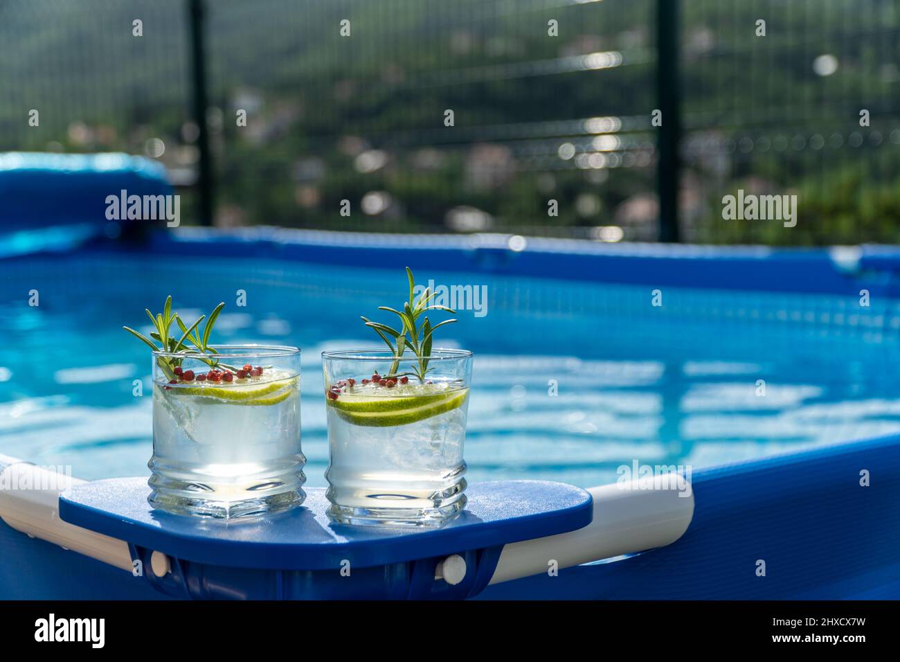 Deux cocktails sur une piscine portable dans un jardin avec vue imprenable sur les montagnes. Banque D'Images