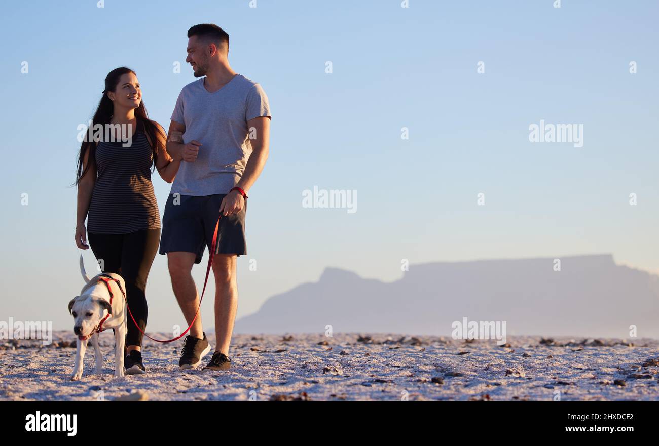Pour notre promenade quotidienne. Photo d'un couple pour marcher à la plage avec son chien. Banque D'Images