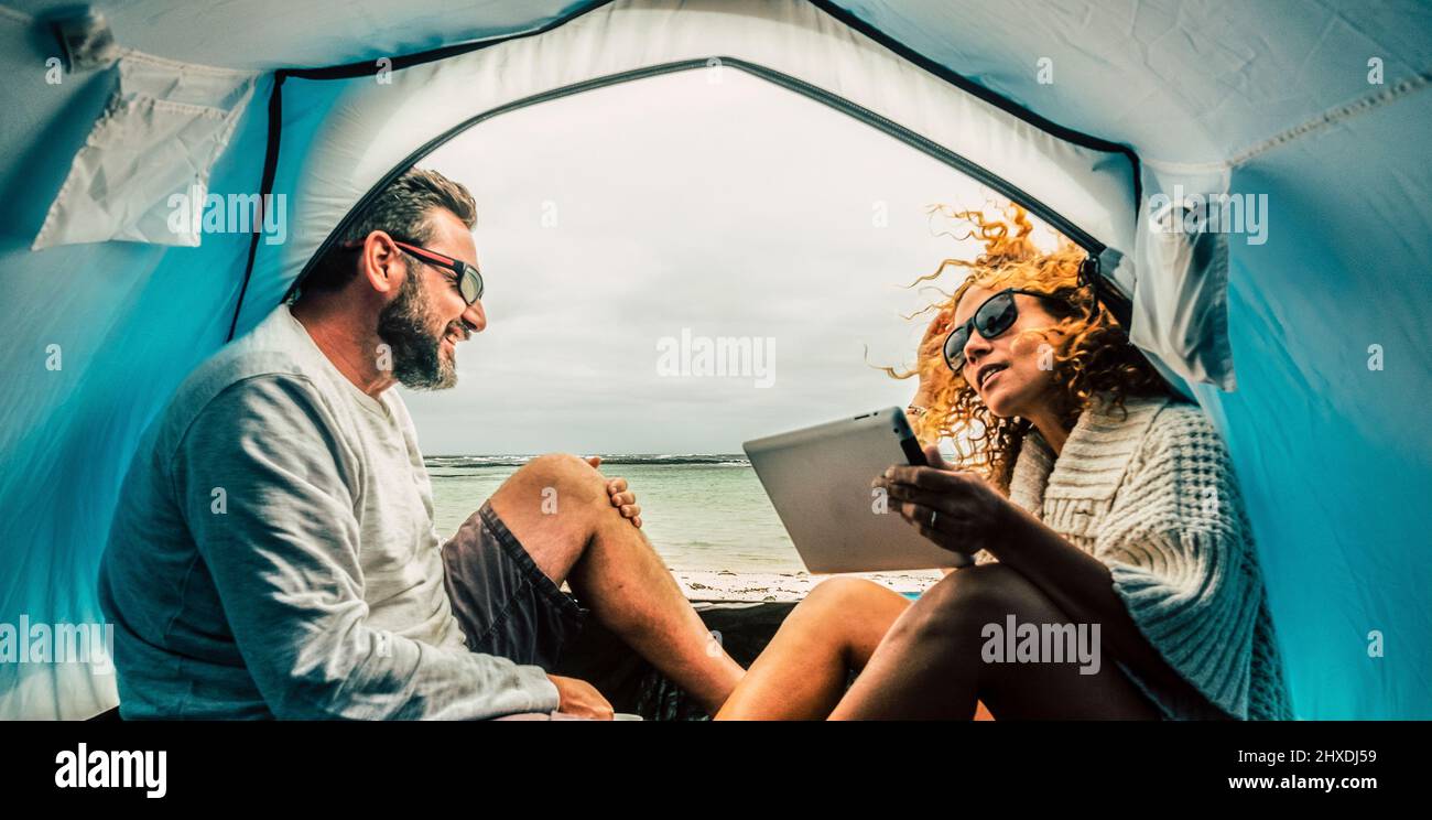 Couple d'adultes caucasiens souriez et profitez de loisirs à l'intérieur d'une tente en camping gratuit à la plage avec vue sur la mer. Concept de tourisme alternatif et de voyage vac Banque D'Images