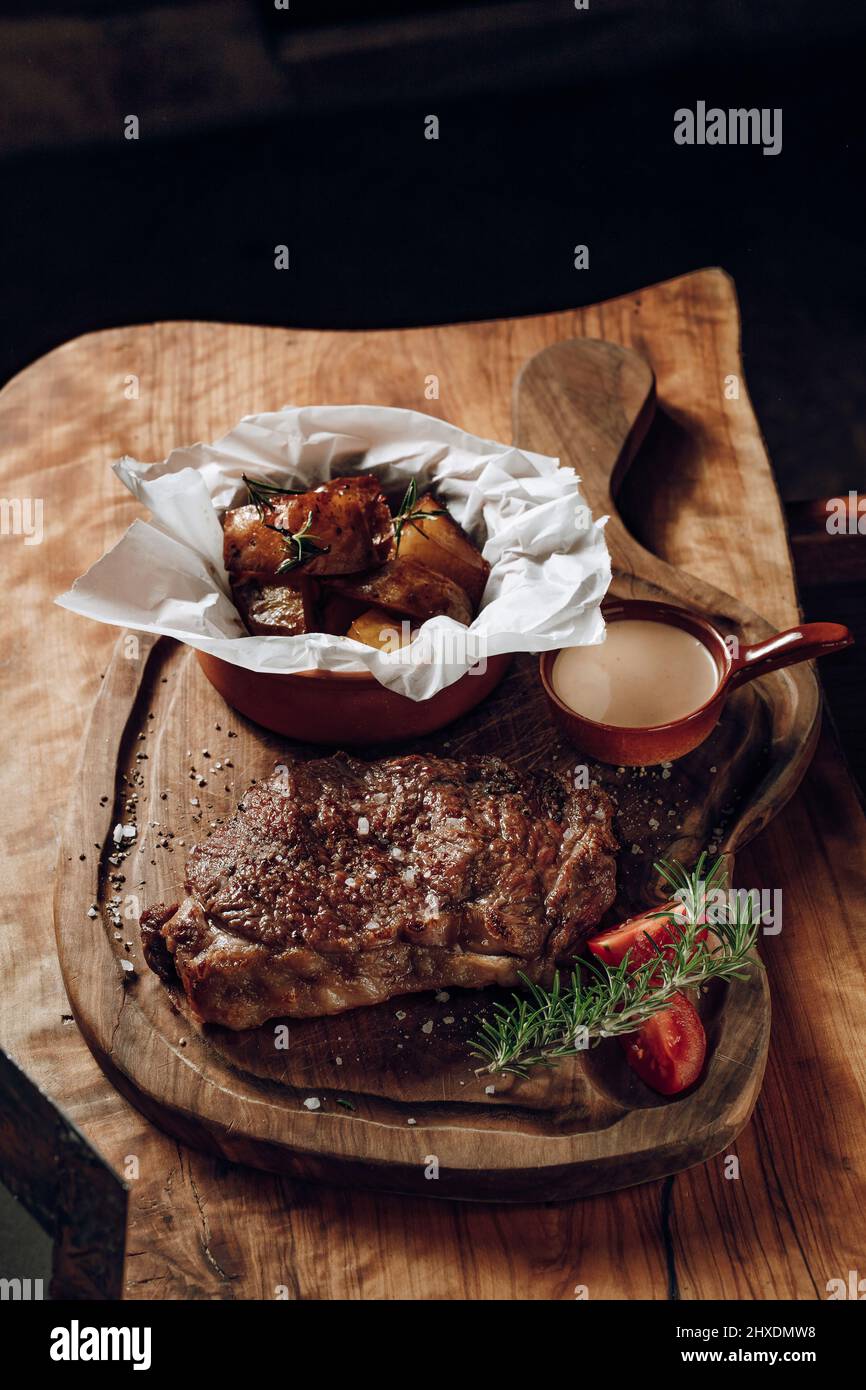 Délicieux steak juteux avec sauce pommes de terre cuites sur une surface en bois Banque D'Images