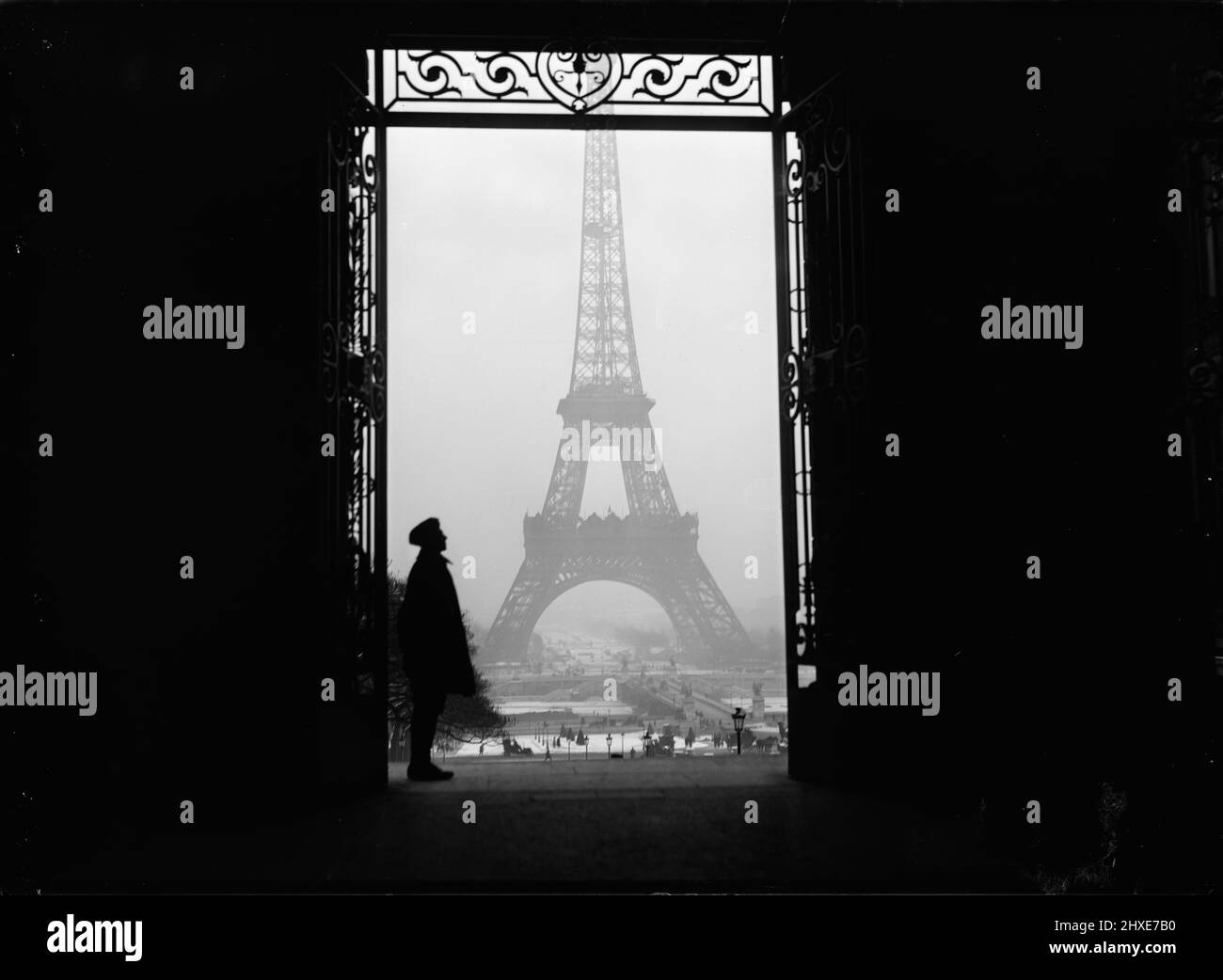 Vintage 1919 photo noir et blanc de la tour Eiffel encadrée par une porte avec une personne debout, Paris, France Banque D'Images