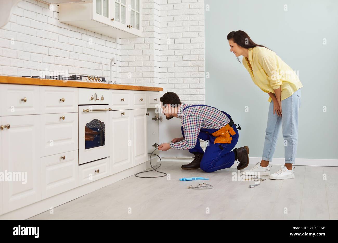 Plombez le nettoyage des tuyaux bouchés sous l'évier de cuisine à l'aide d'un câble d'évacuation Banque D'Images