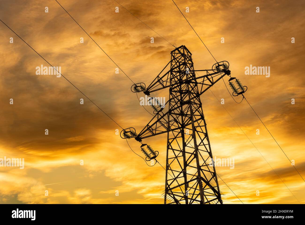 Tour haute tension sur ciel nuageux et coloré de coucher de soleil Banque D'Images