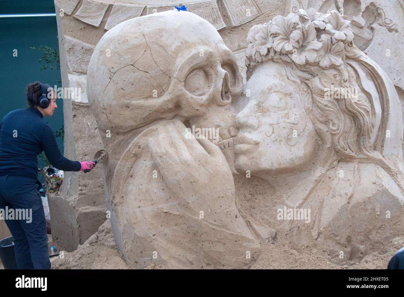 Binz, Allemagne. 11th mars 2022. Une femme travaille sur une sculpture de sable du spectacle de sculpture de sable 'quel monde merveilleux'. Les sculptures représentent des paysages, des gens et des créatures mythiques. Credit: Stefan Sauer/dpa/Alay Live News Banque D'Images