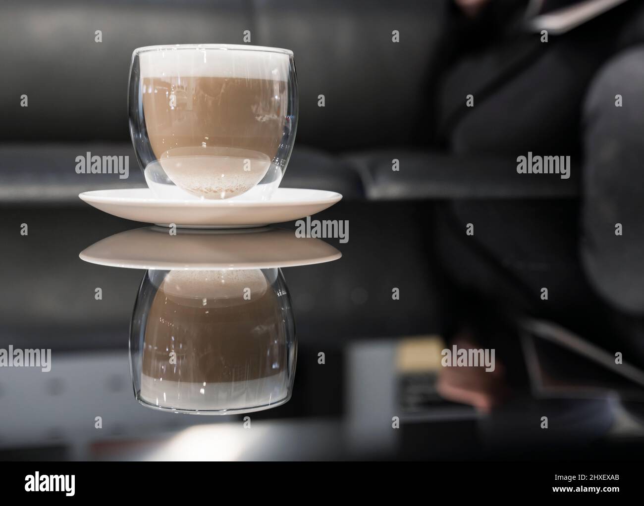 Une tasse de café cappuccino avec mousse sur une table en verre noir Banque D'Images