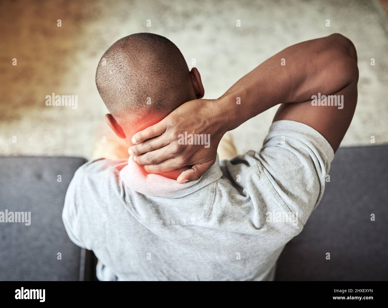 J'aurais dû mal dormir la nuit dernière. Vue arrière d'un homme méconnaissable tenant son cou à l'aise tout en étant assis sur un canapé à la maison. Banque D'Images