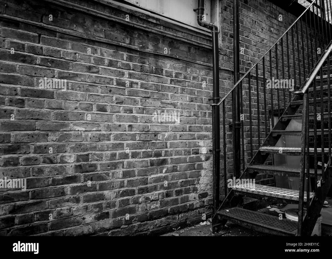 Une ancienne allée de briques avec escalier en fer noir et blanc Banque D'Images