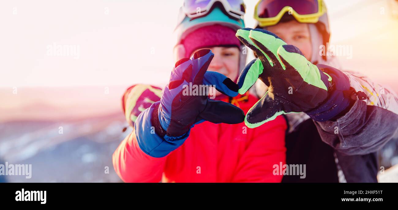 Snowboarders homme et femme montrent coeur signe avec les mains, Voyage hiver amour bannière concept. Banque D'Images