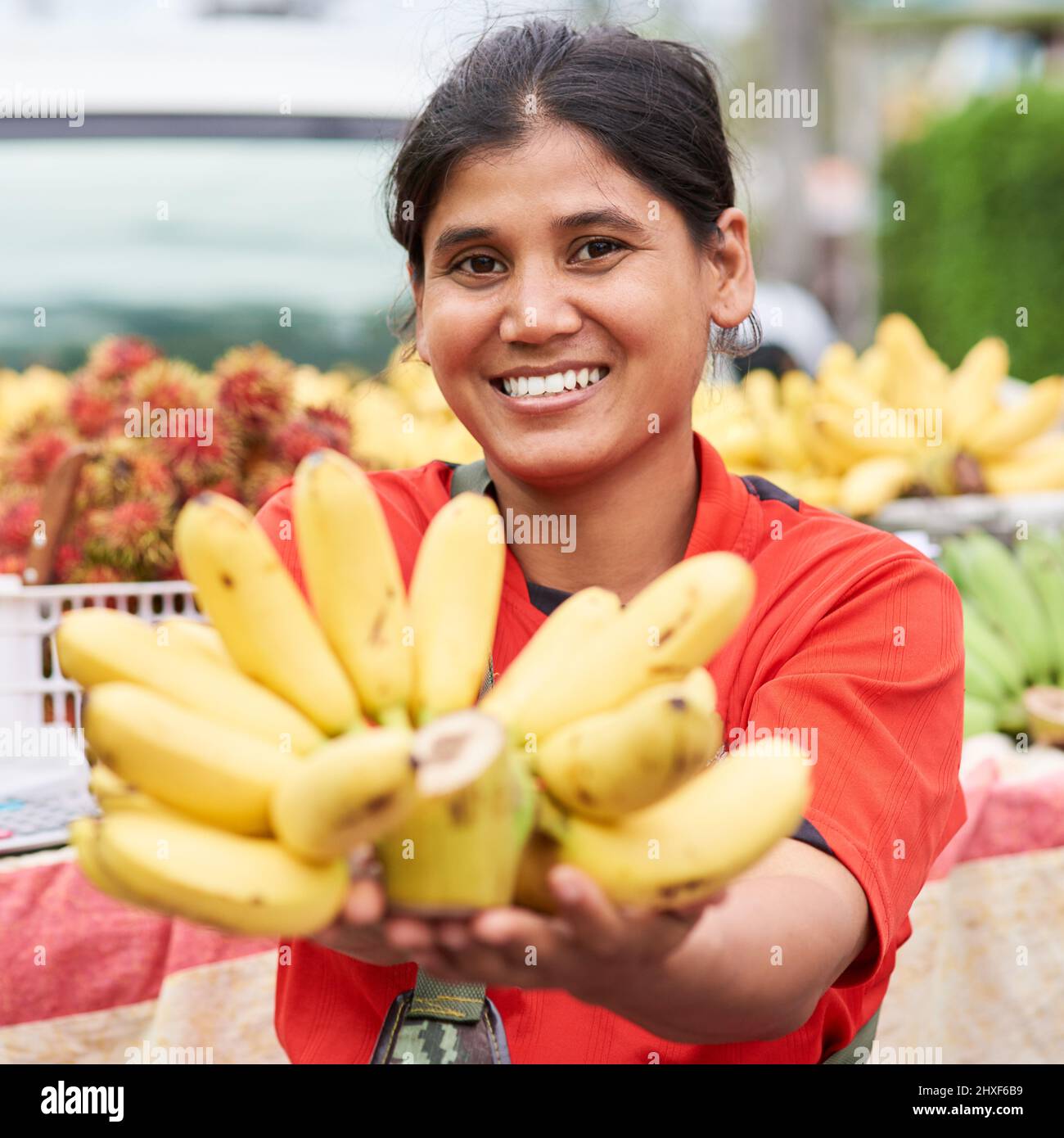 Bananes fraîches. Portrait d'une femme qui vend des bananes à son marché stalle à l'extérieur. Banque D'Images