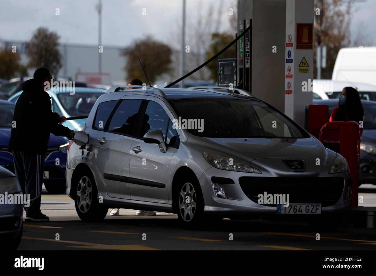 Un chauffeur ravitaille une voiture dans une station-service à bas prix,  tandis que d'autres conducteurs continuent de faire la queue, car le prix  de l'essence continue d'augmenter, à Getafe, Espagne, le 12